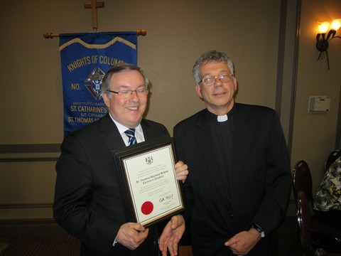 St. Catharines MPP Jim Bradley presents Father Michael with a certificate from the Province of Ontario